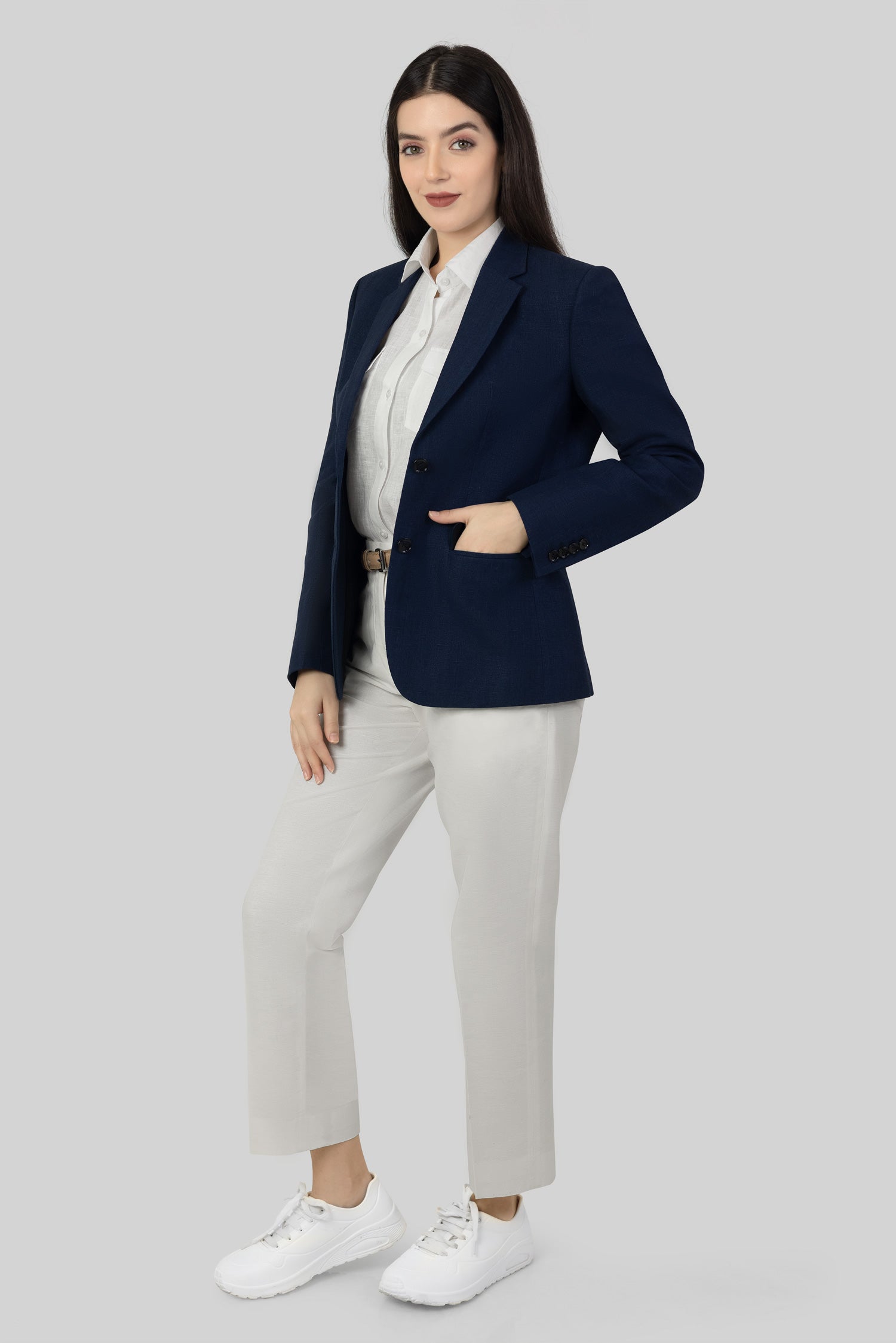 A woman modeling a blue linen blazer with a notch lapel, two-button single-breasted design, and flap pockets.