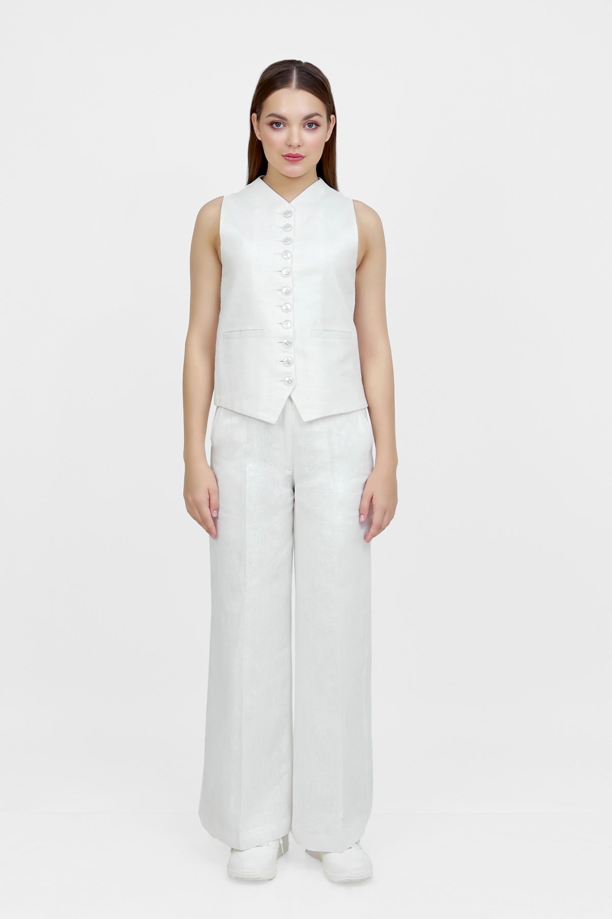 Woman wearing a white sleeveless top and wide-leg pants on a white background