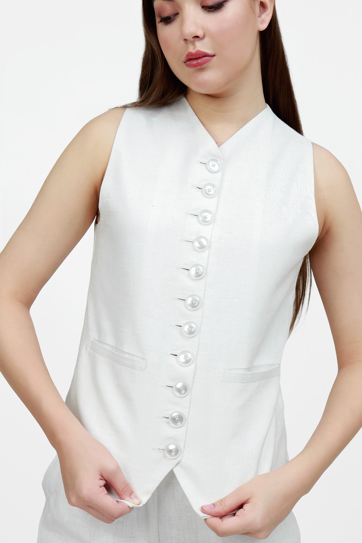 Woman wearing a white sleeveless top and wide-leg pants on a white background