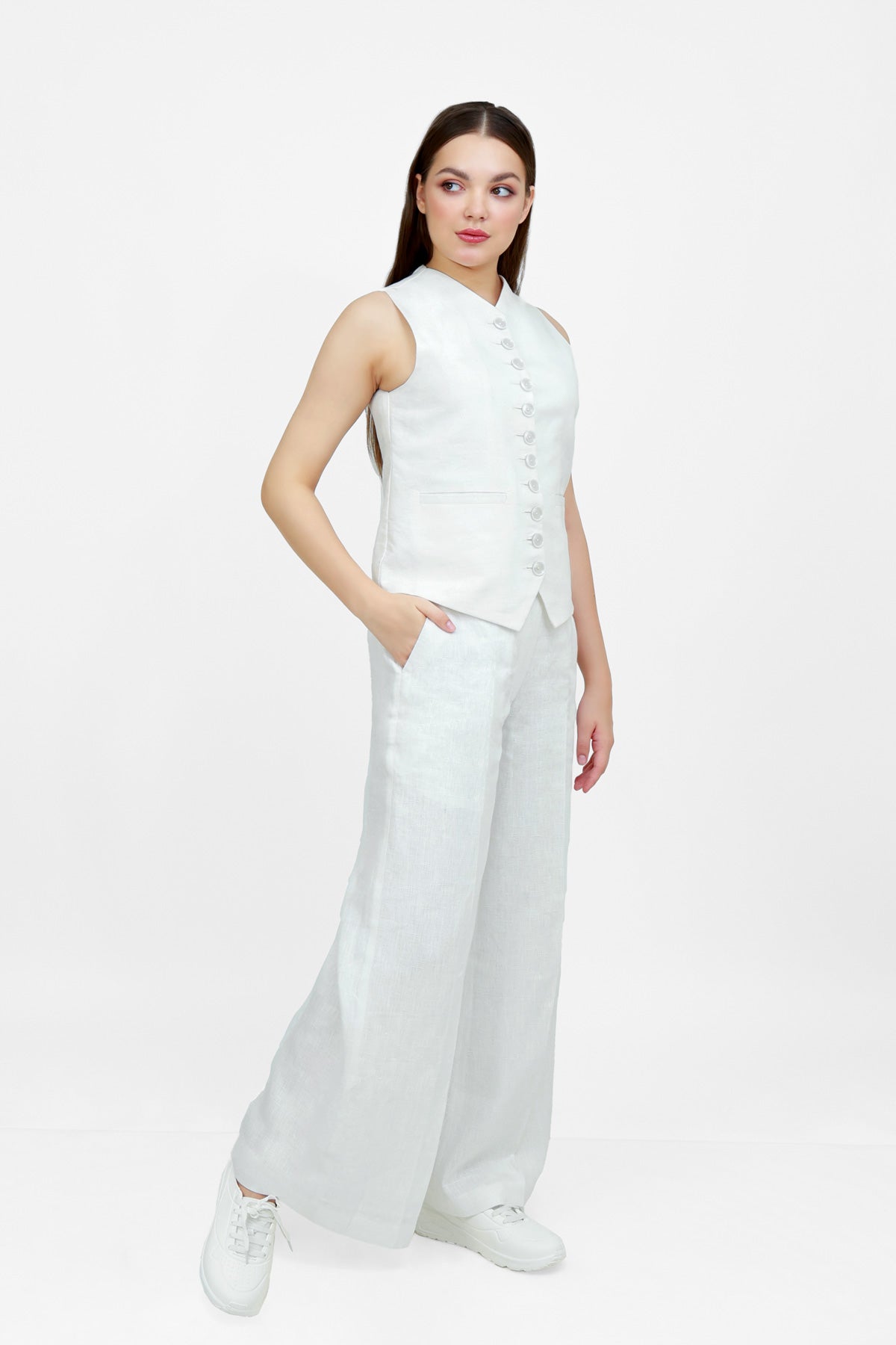 Woman wearing a white sleeveless top and wide-leg pants on a white background