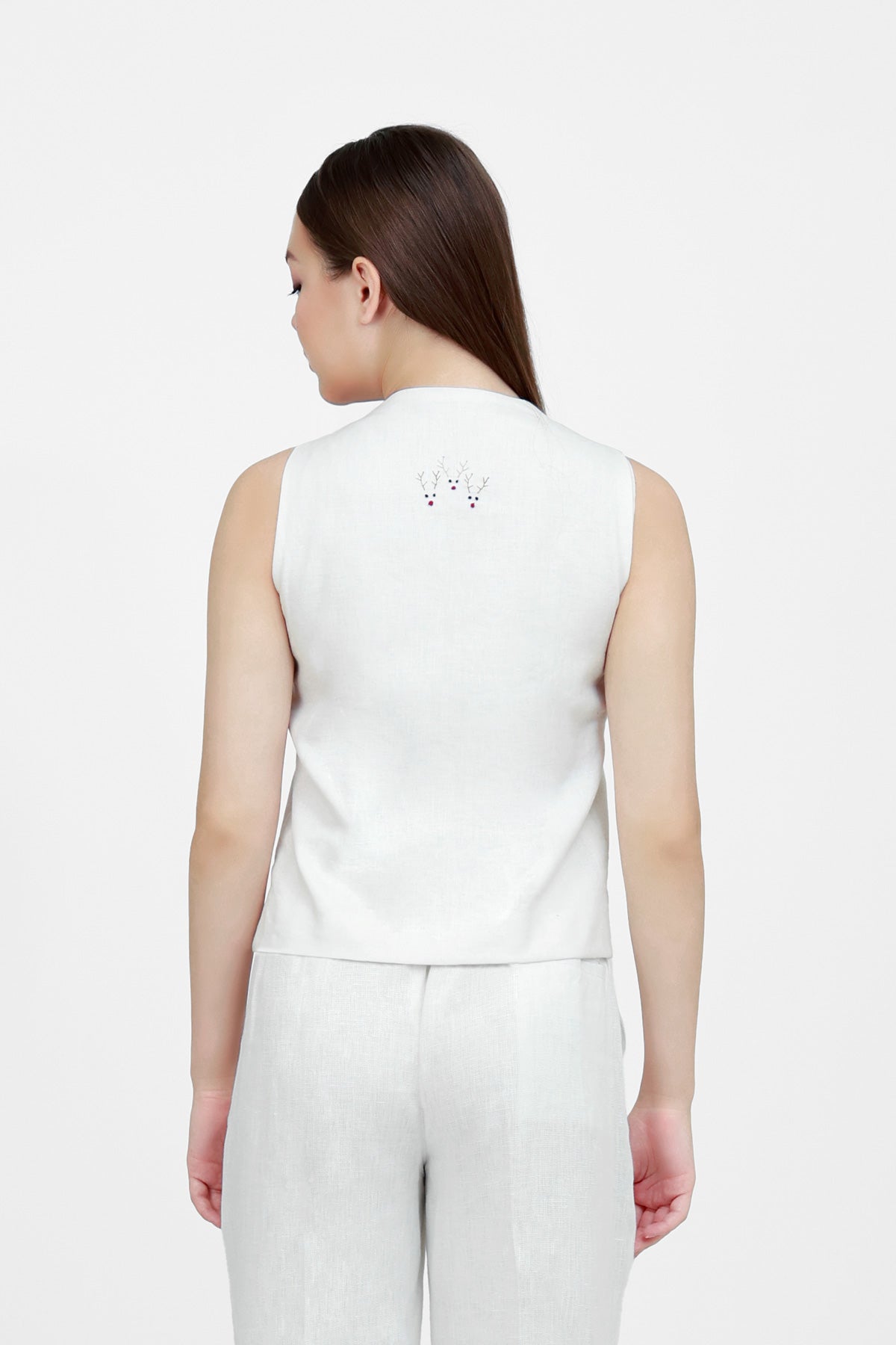 Woman wearing a white sleeveless top and wide-leg pants on a white background