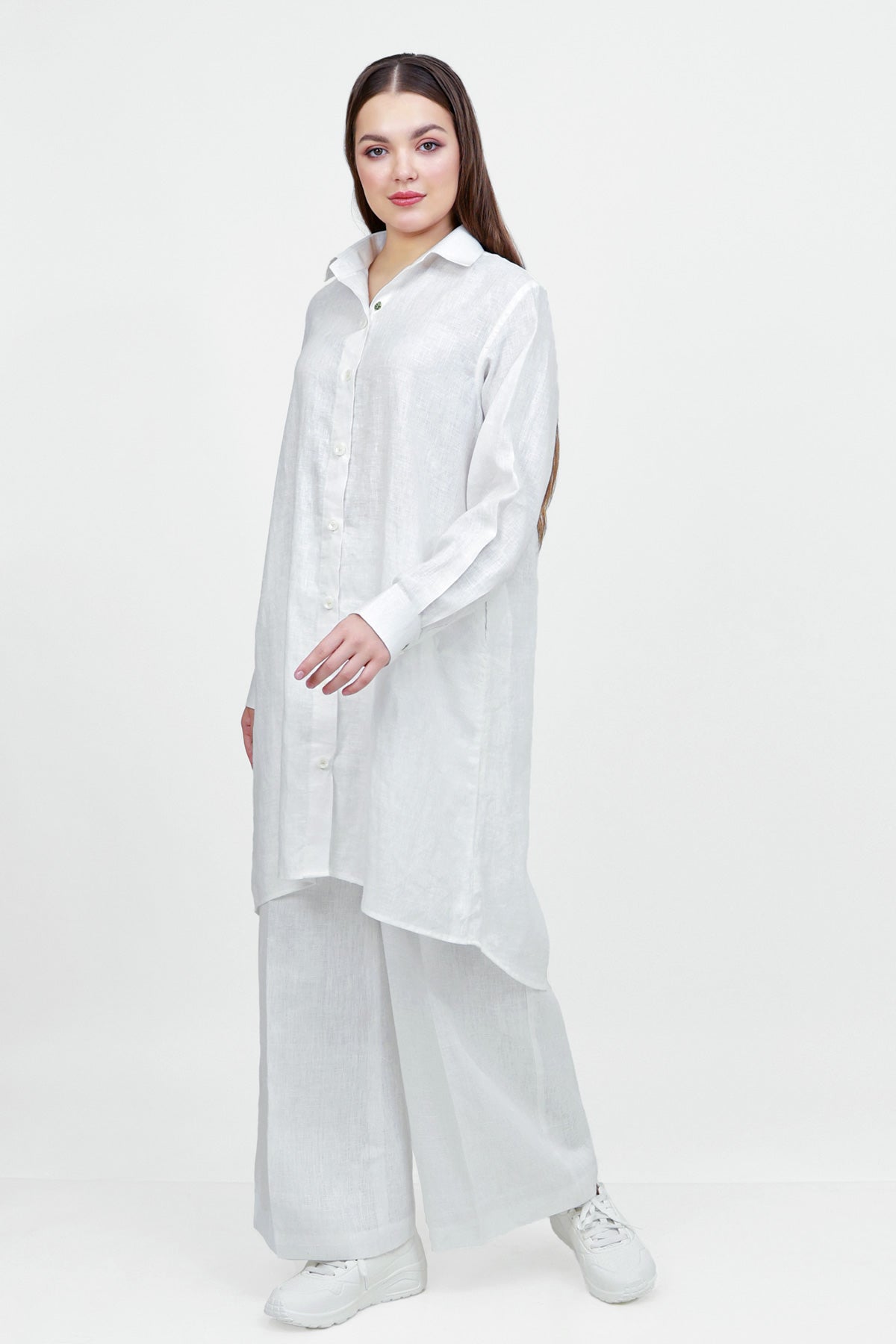 Woman wearing a long white shirt and pants on a white background