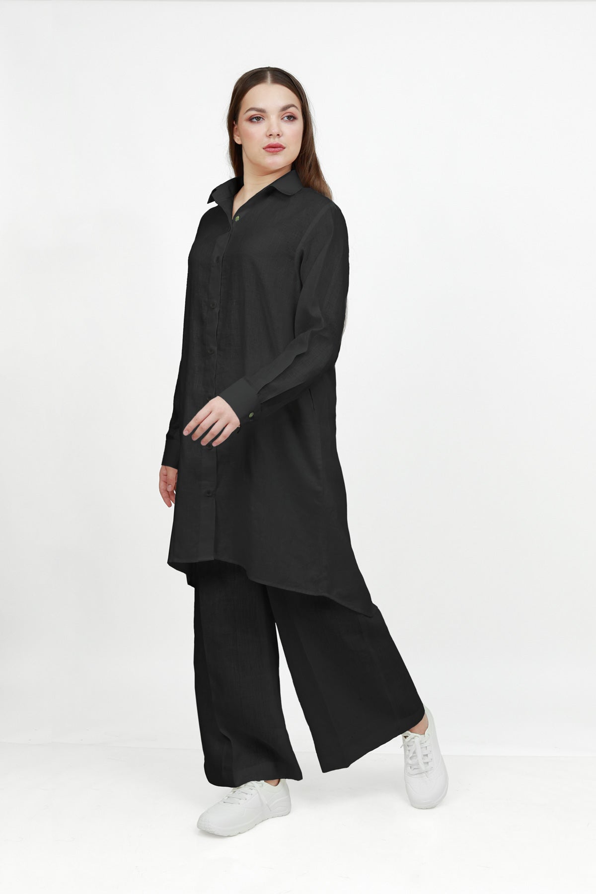 Woman wearing a black long-sleeve shirt and wide-leg pants on a white background