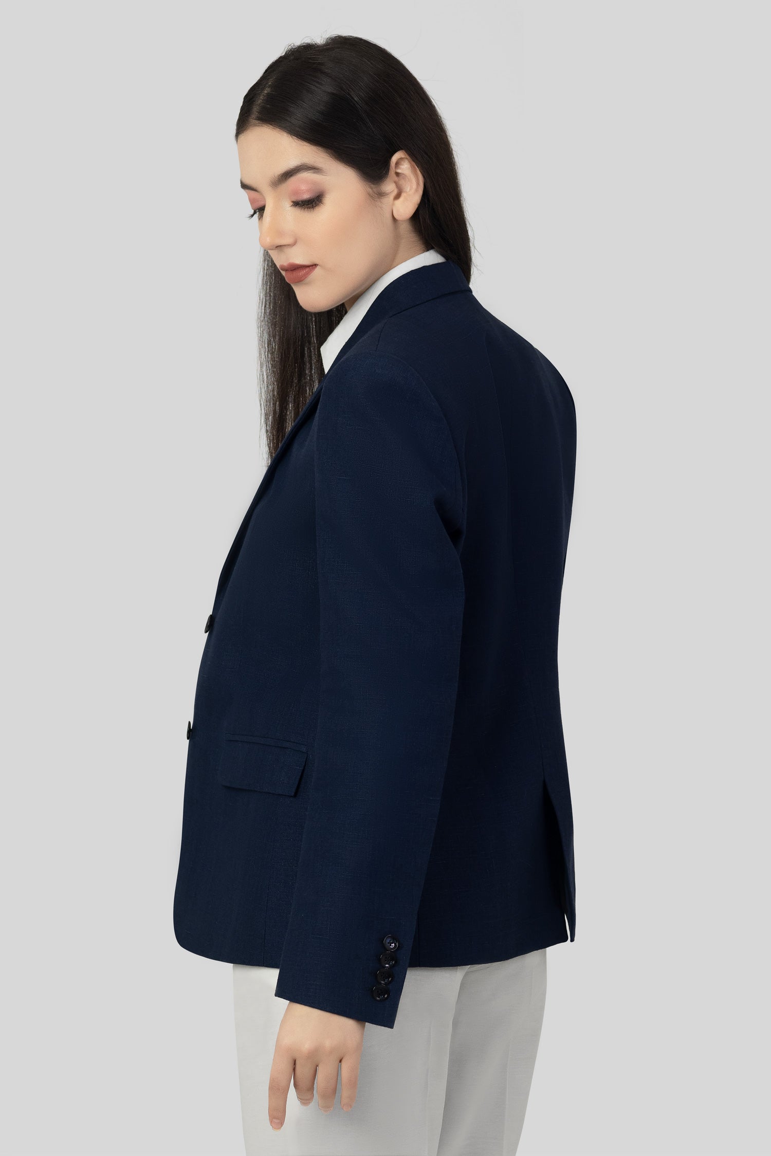 A woman modeling a blue linen blazer with a notch lapel, two-button single-breasted design, and flap pockets.