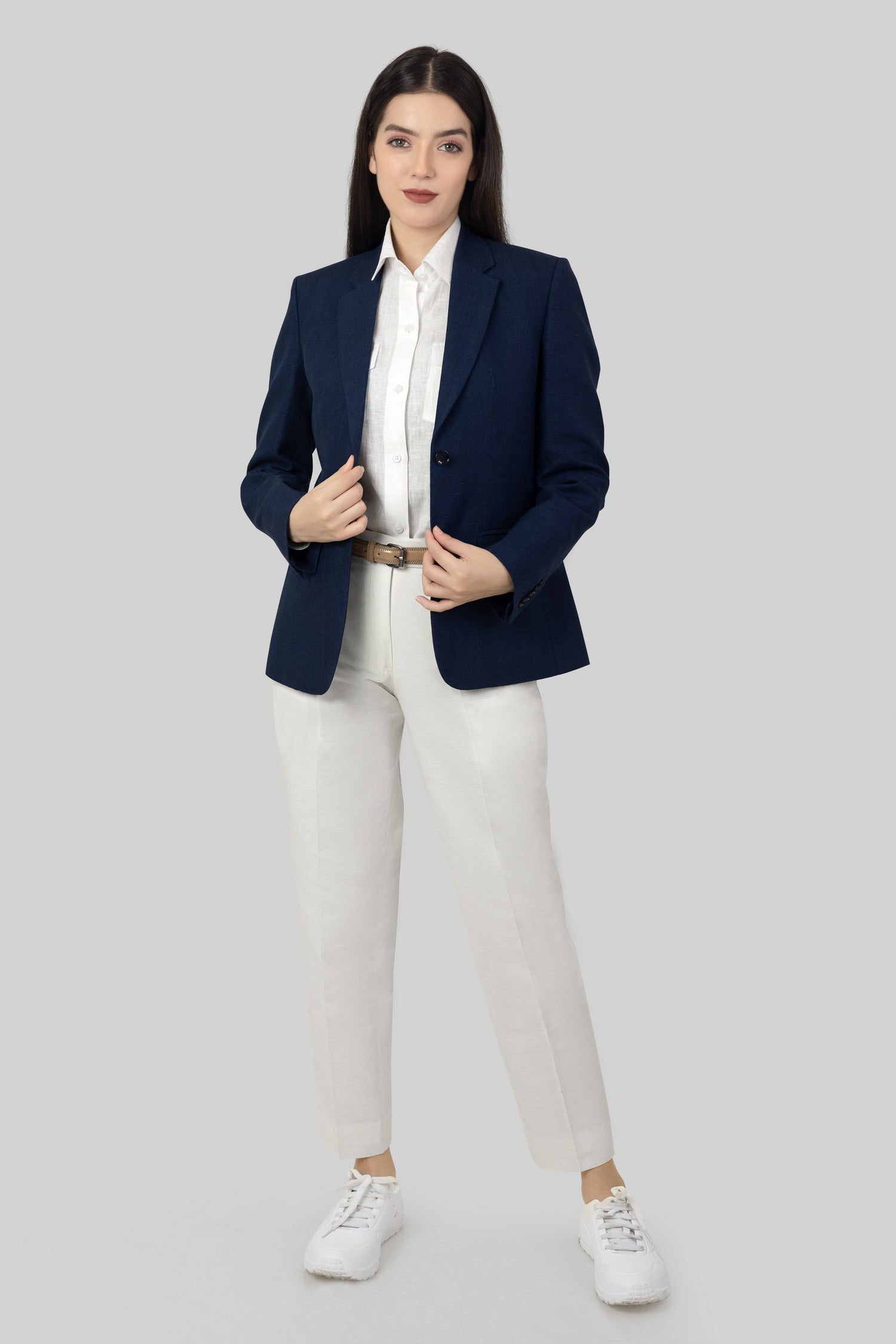 A woman modeling a blue linen blazer with a notch lapel, two-button single-breasted design, and flap pockets.