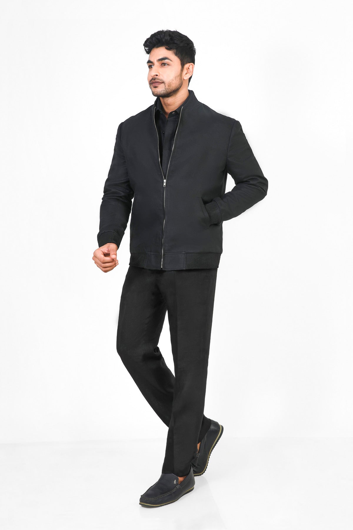 Man wearing a black jacket and pants on a white background