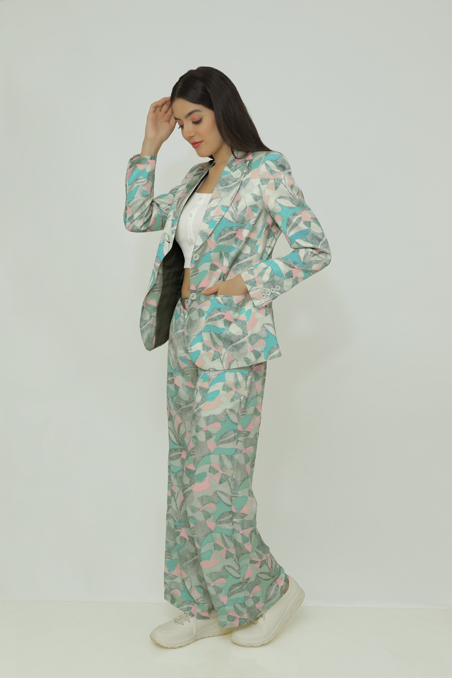 A female model wearing a floral print silk blazer with notch lapel, single-breasted with two buttons, and functional sleeves with four buttons.