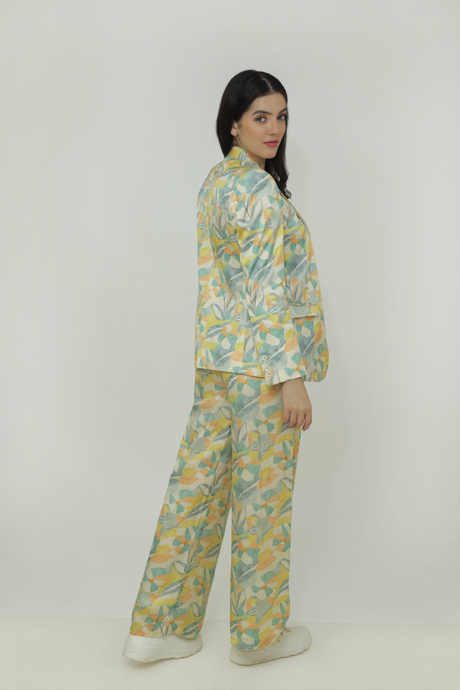 A woman modeling a floral silk blazer with a notch lapel and two-button closure. The blazer is in a light multicolor pattern.