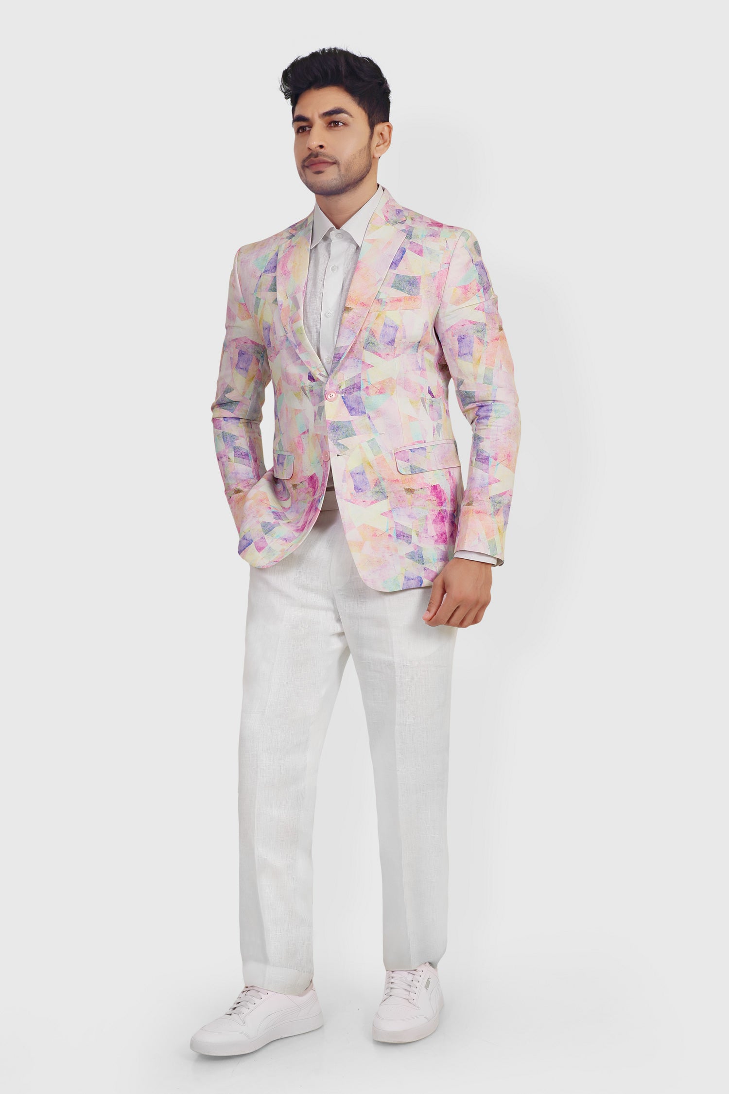 Man wearing a colorful blazer with a white shirt and pants on a light gray background