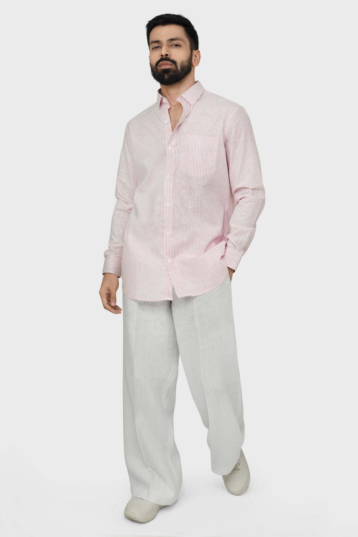 Man wearing a light pink shirt and beige pants on a white background