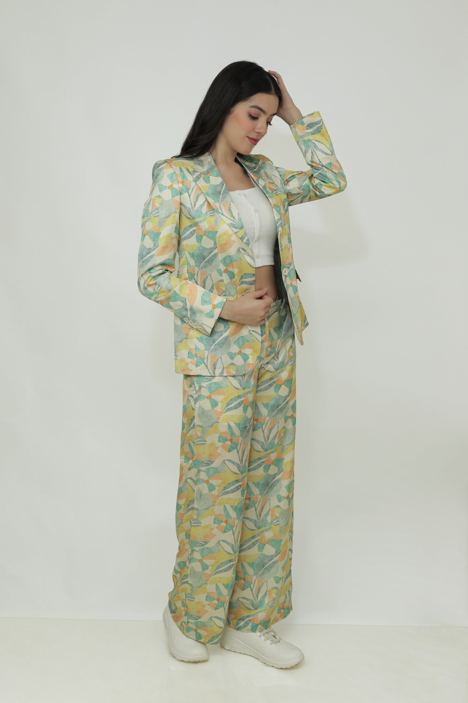 A woman modeling a floral silk blazer with a notch lapel and two-button closure. The blazer is in a light multicolor pattern.