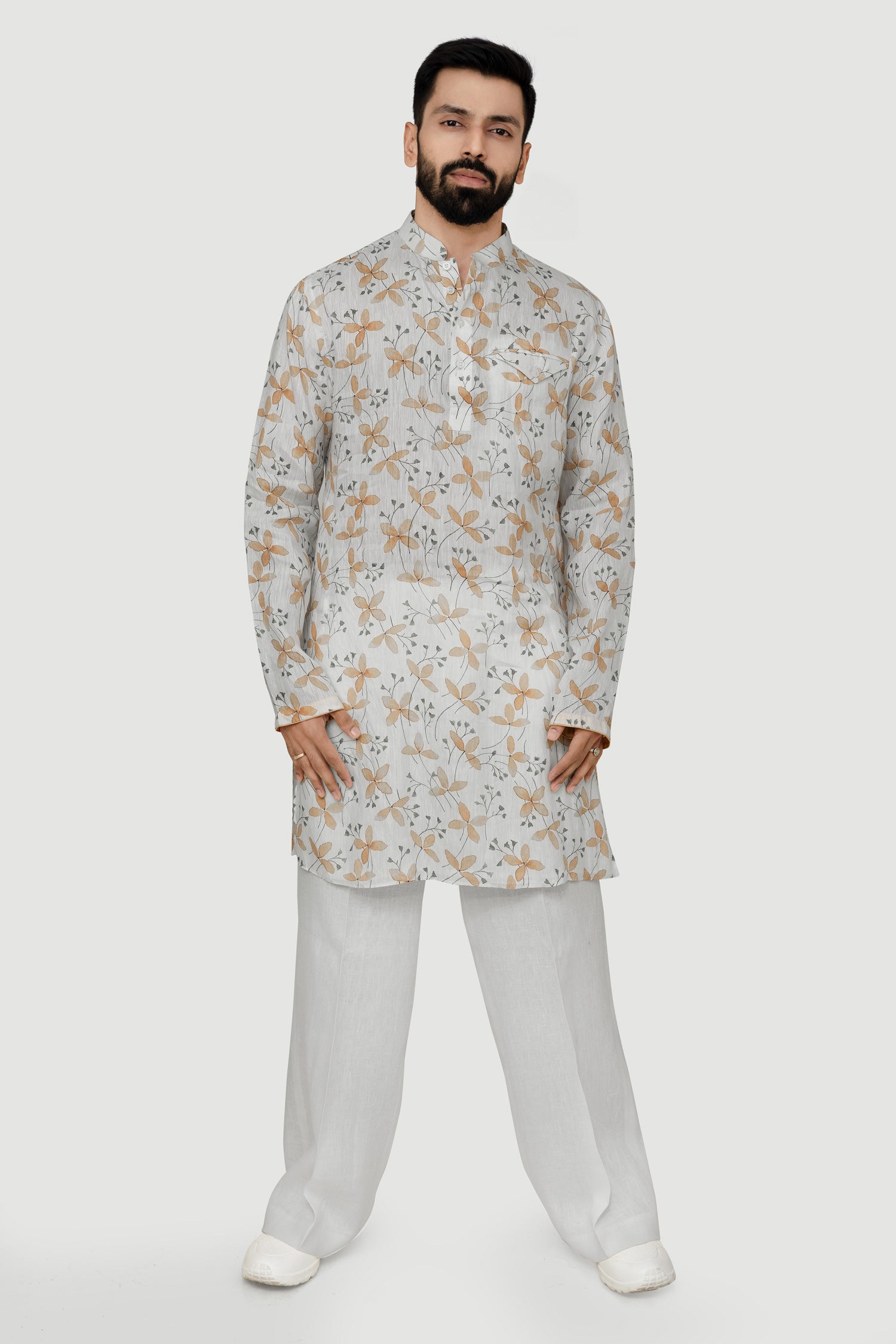 A man wearing a traditional Indian linen kurta with a mandarin collar, featuring a floral print and matching buttons, paired with light-colored trousers.