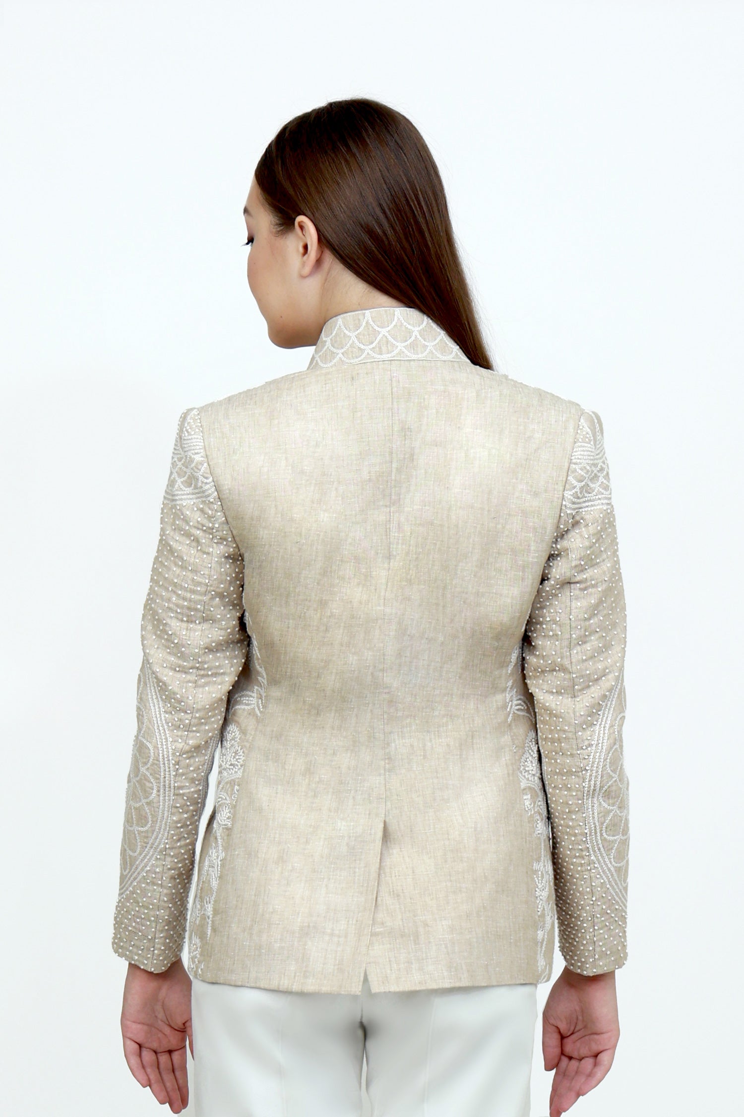 Woman wearing a beige embroidered jacket on a white background