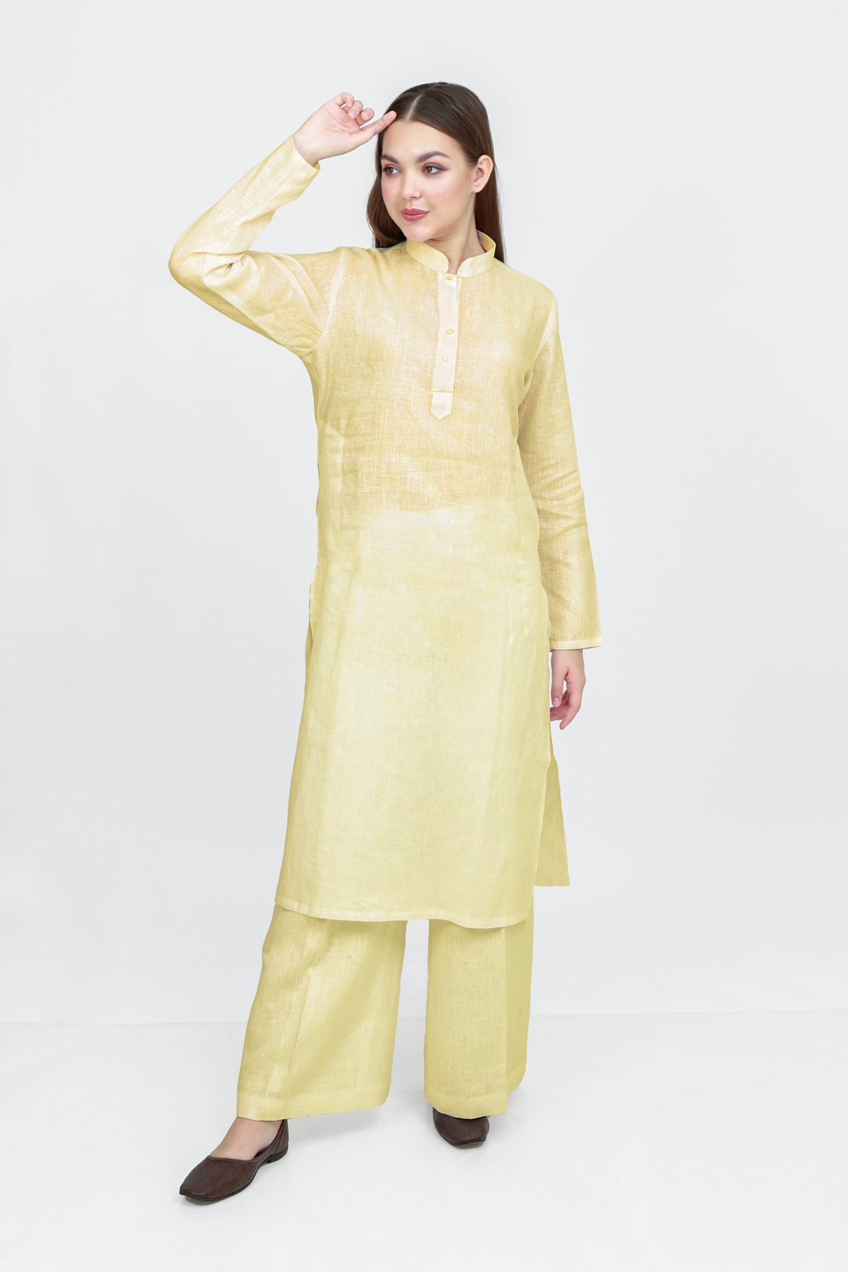 Woman wearing a light yellow kurta with palazzo pants on a white background