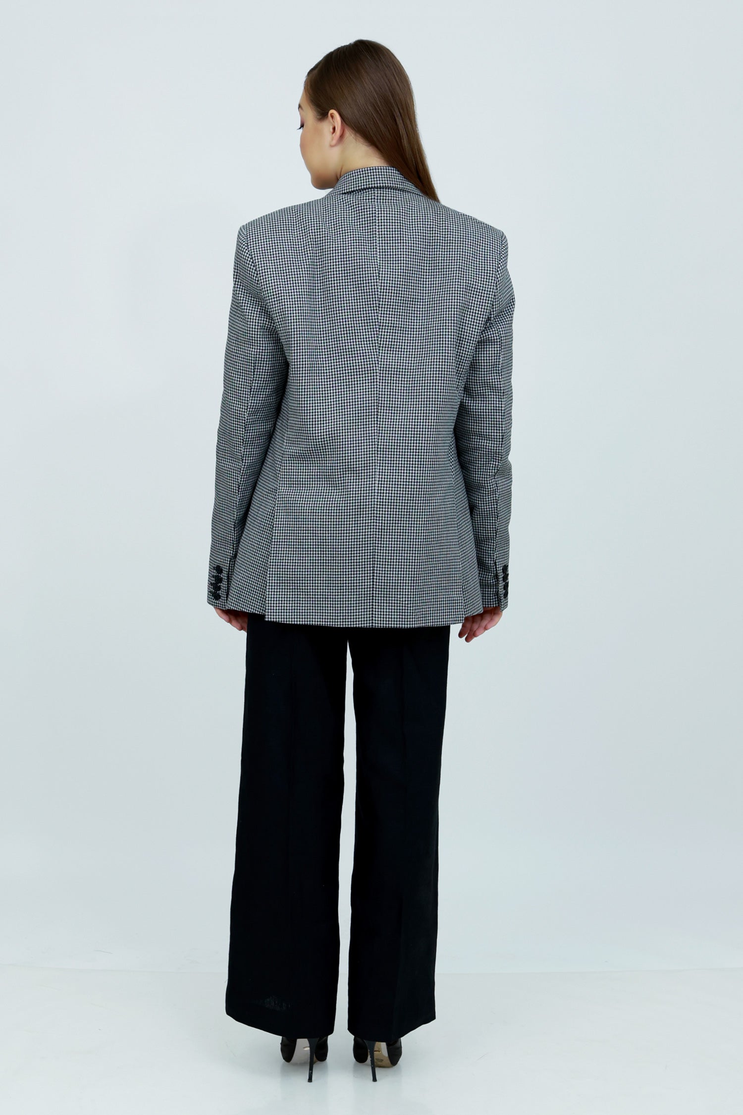 A woman wearing a gray and white patterned cotton blazer, a black button-down shirt, and black wide-leg trousers.