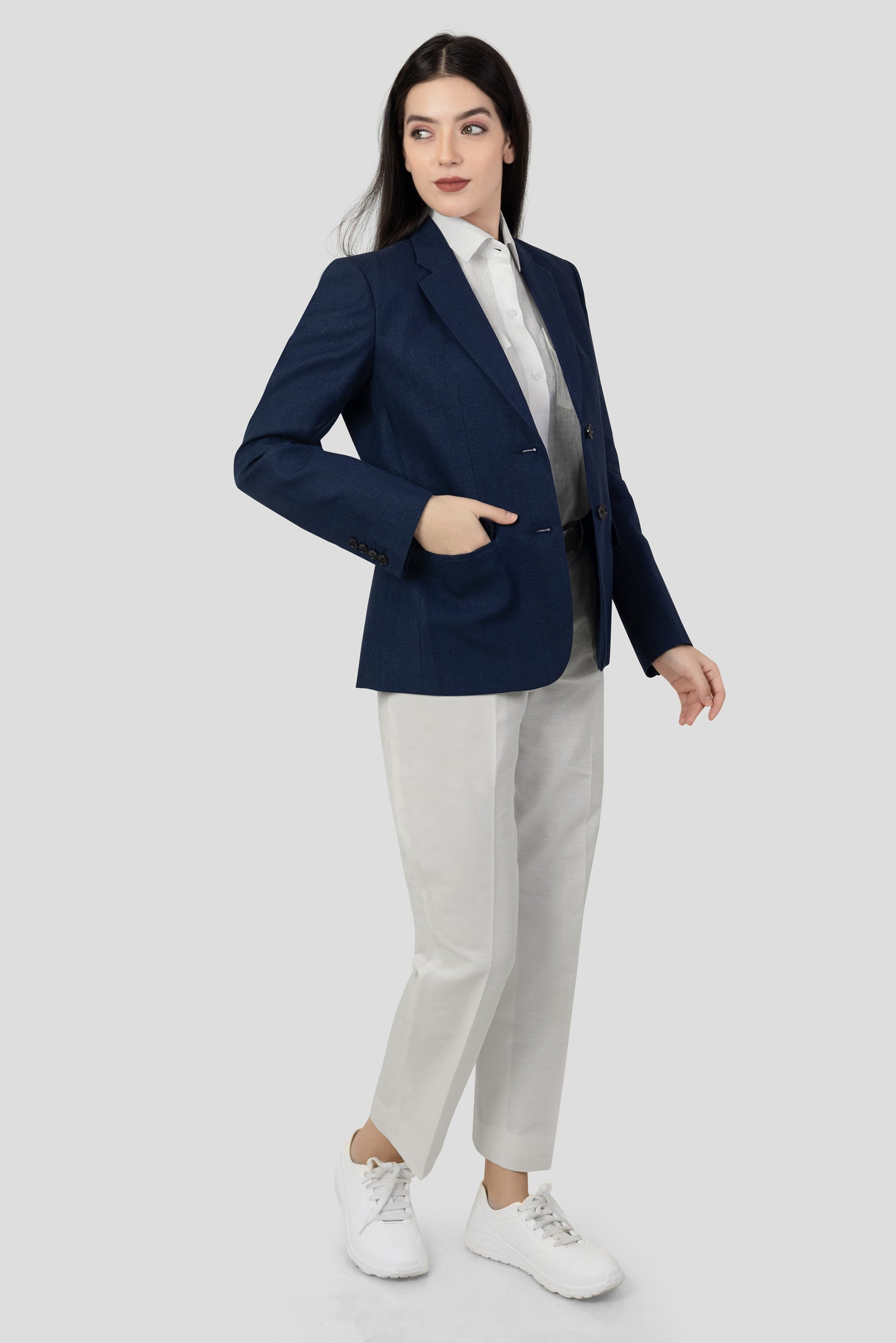 A woman modeling a blue linen blazer with a notch lapel, two-button single-breasted design, and flap pockets.