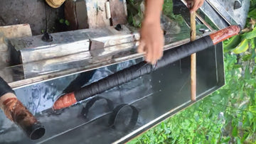 Fabric bundle with red-capped ends being wrapped and prepared for steaming outdoors