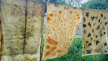 Three eco-printed fabrics with botanical leaf patterns hanging on a line to dry in the shade