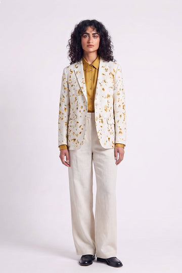 A model wearing a cream hemp blazer with a yellow and brown botanical eco-print.