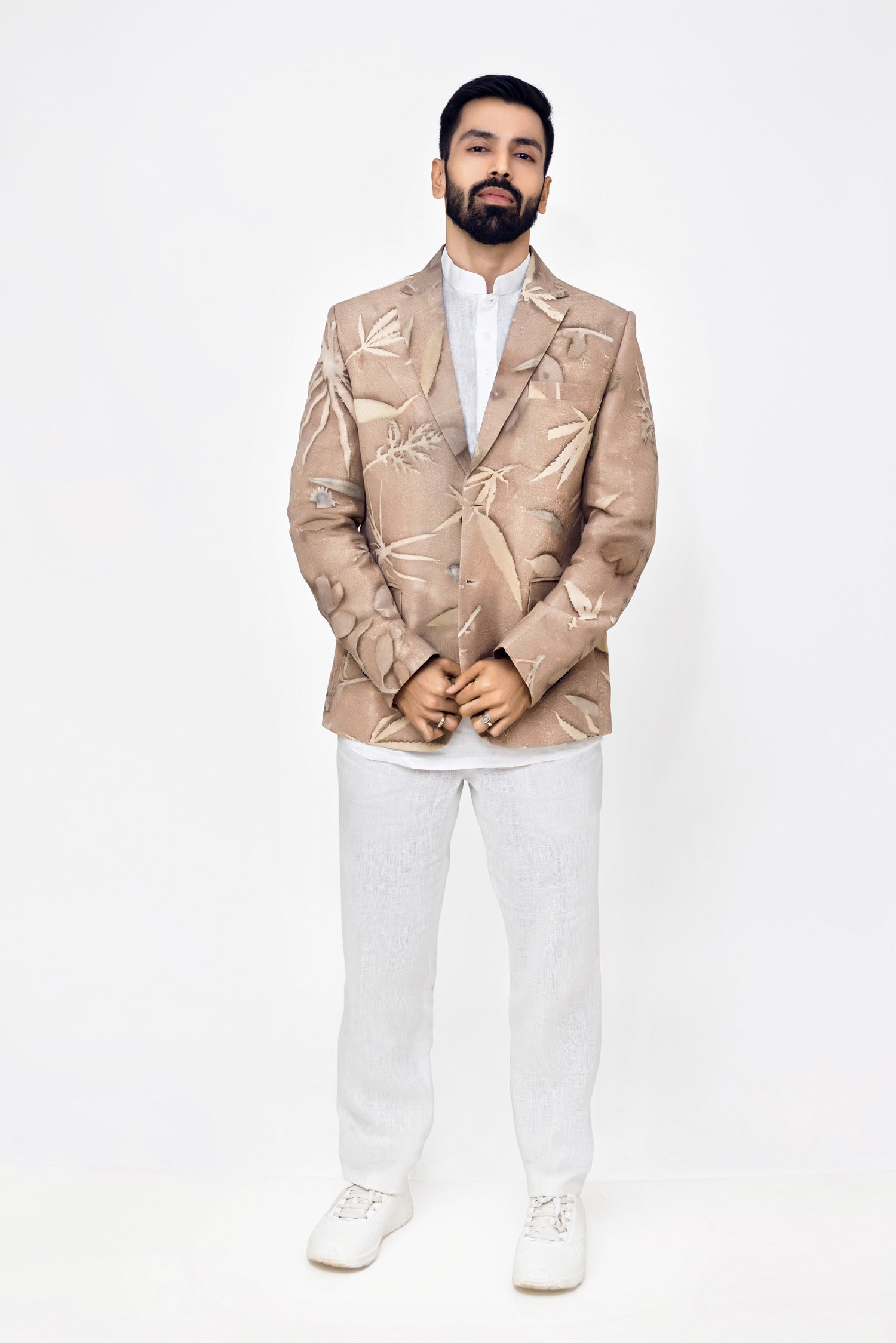 Man wearing a beige Eco-printed blazer over a white shirt and pants on a white background