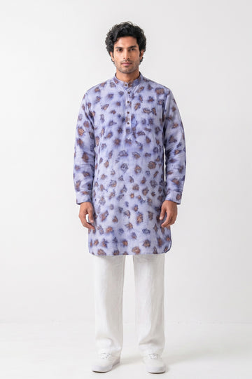 A man modeling a light purple/lavender long-sleeve kurta with a brown and purple floral pattern, paired with white trousers and white sneakers, against a plain white studio background.