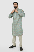 A man wearing a traditional Indian linen kurta with a mandarin collar, featuring a floral print and matching buttons, paired with light-colored trousers.