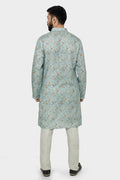 A man wearing a traditional Indian linen kurta with a mandarin collar, featuring a floral print and matching buttons, paired with light-colored trousers.