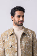 A man wearing a beige and white patterned hemp jacket over a cream turtleneck sweater, photographed against a light gray studio background.