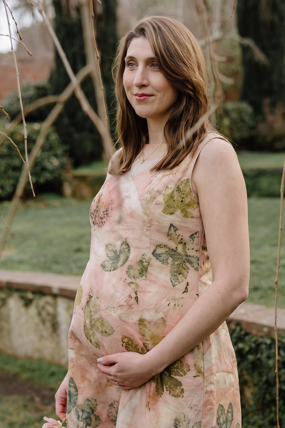 Woman in a floral dress standing on a path surrounded by greenery
