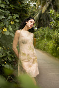 Woman in a floral dress standing on a path surrounded by greenery