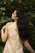 Woman with long, wavy hair standing against a green leafy background