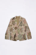 A men's single-breasted blazer with a muted botanical and eco- print in beige, pink, and brown tones, laid flat against a white background.