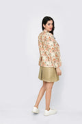 Woman wearing a floral linen blazer and beige skirt on a white background