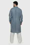 A man wearing a blue linen kurta with a mandarin collar, button placket at the waist, and side pockets. The kurta has a relaxed fit and side slits.