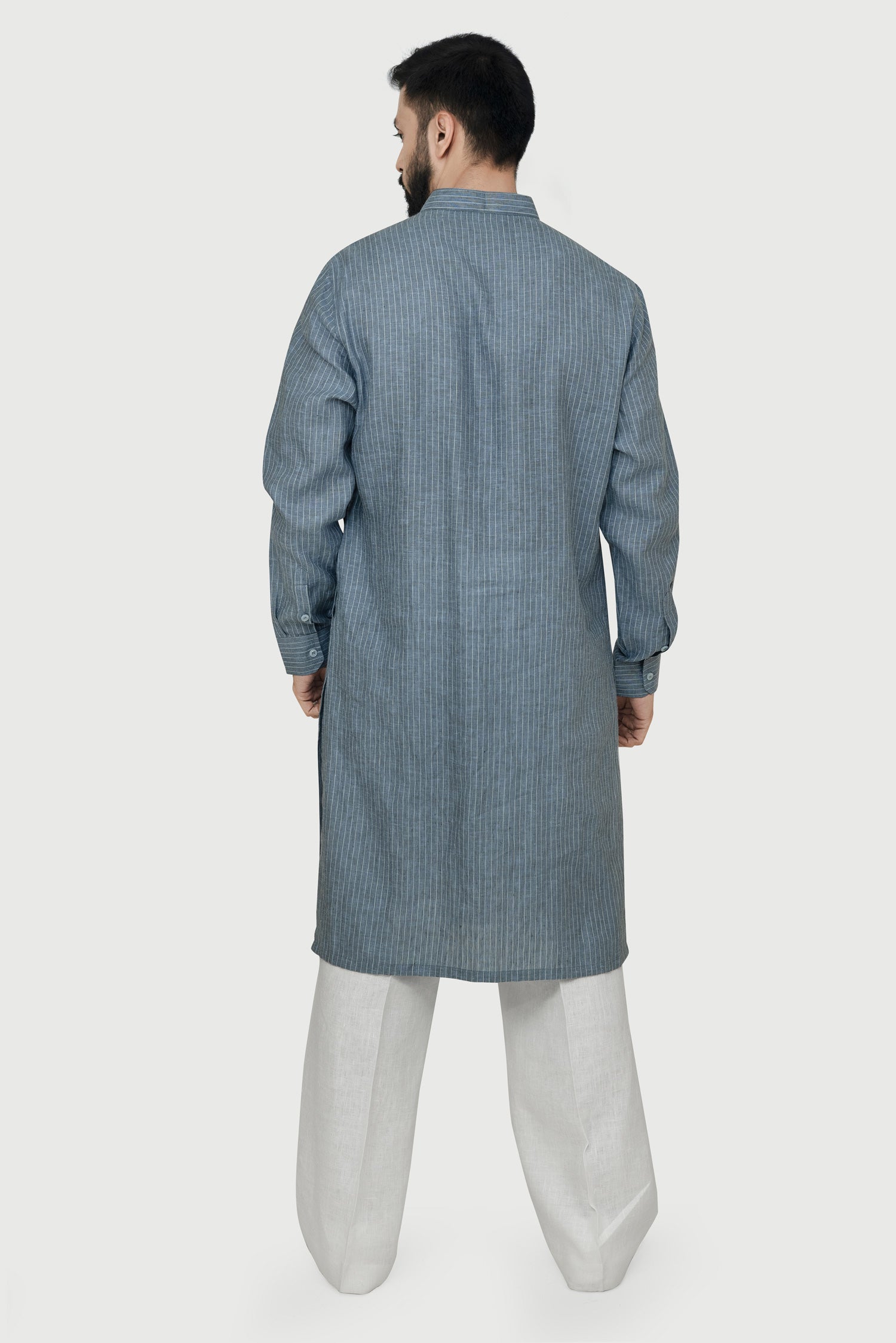 A man wearing a blue linen kurta with a mandarin collar, button placket at the waist, and side pockets. The kurta has a relaxed fit and side slits.