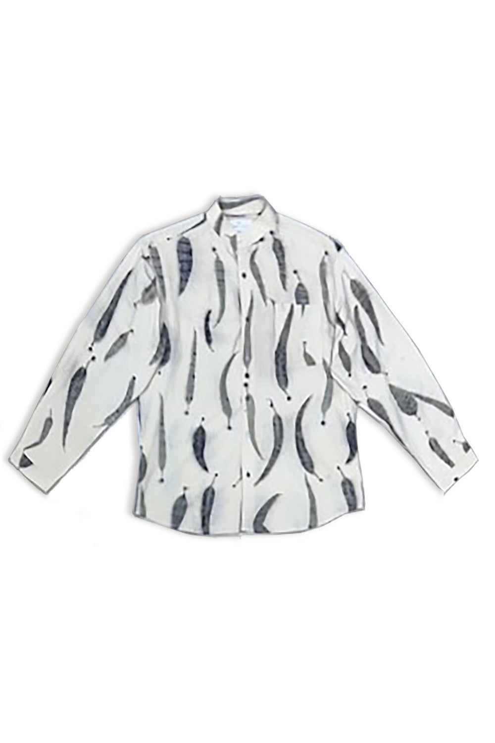 A man modeling a cream-colored long-sleeve button-up shirt with a black abstract leaves eco-print pattern, paired with black trousers and black sneakers, standing against a white textured wall.