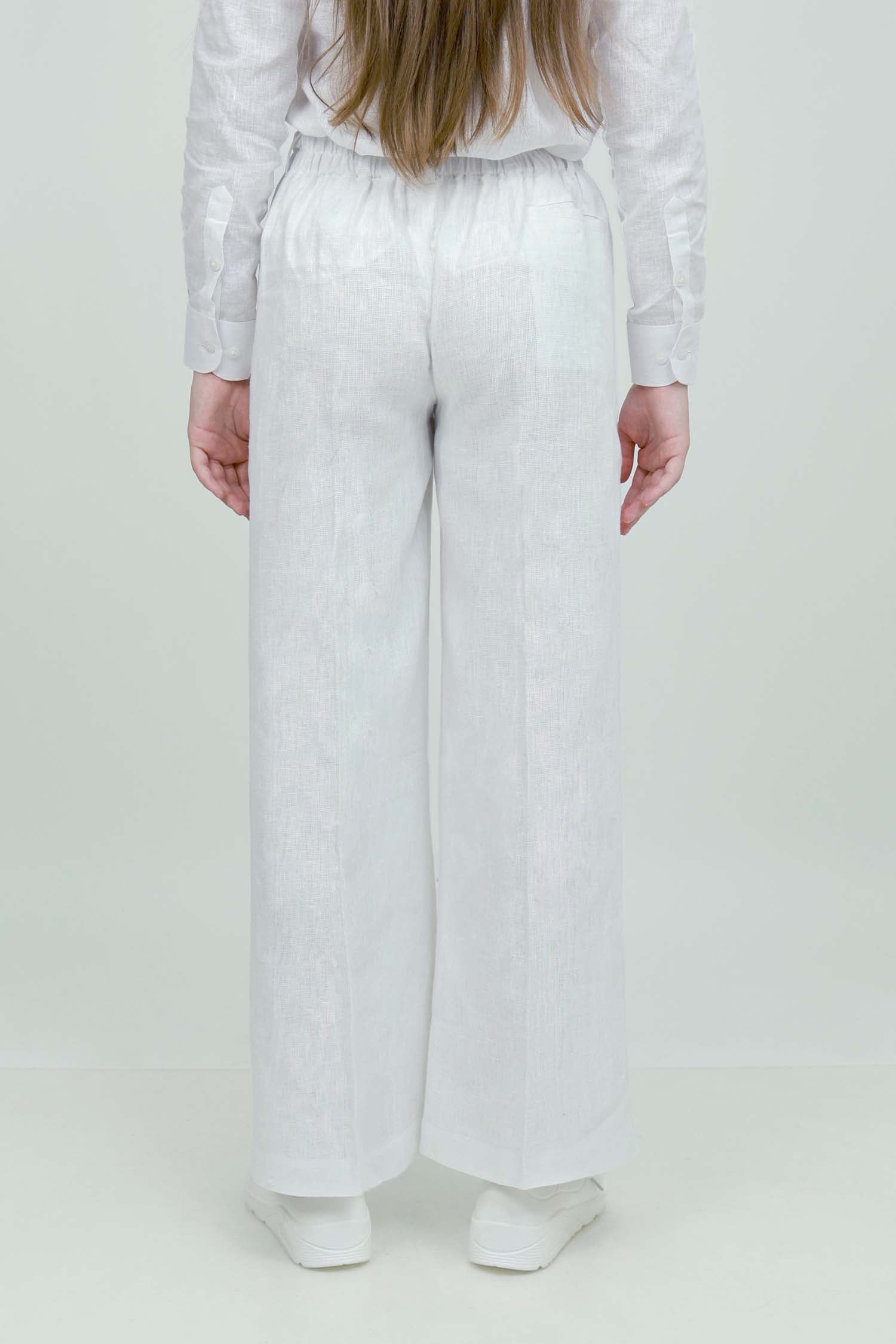A pair of white wide-leg trousers with a mid-rise waist, front buttons, and a relaxed fit. The trousers are fully lined and have a hook and bar closure at the waistband with an adjustable elastic belt.