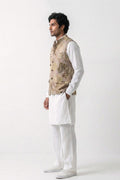 A man modeling a traditional Indian outfit consisting of a white kurta and trousers paired with a beige eco-printed hemp waistcoat, standing in profile against a white studio background.