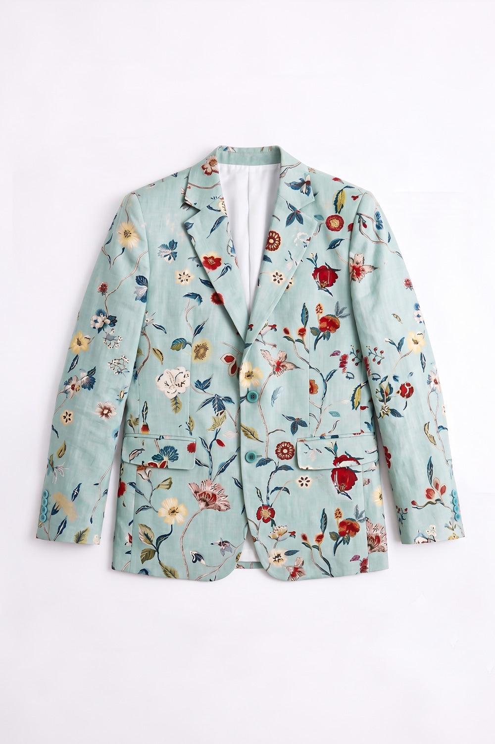 A model stands against a plain white studio background wearing a mint green floral patterned linen blazer over a white t-shirt and white wide-leg trousers.