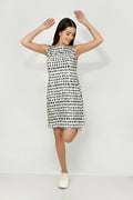 A woman wearing a sleeveless, knee-length black and white hemp dress with a boat neckline, standing before white background