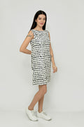 A woman wearing a sleeveless, knee-length black and white hemp dress with a boat neckline, standing before white background