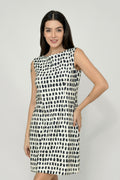 A woman wearing a sleeveless, knee-length black and white hemp dress with a boat neckline, standing before white background