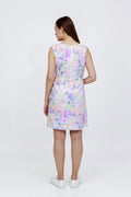 A woman viewed from the back wearing a sleeveless A-line hemp dress with a pastel multicolor floral print, paired with white sneakers, against a plain white studio background.