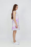 A woman modeling a sleeveless A-line hemp dress with a pastel multicolor abstract print, paired with white sneakers, photographed against a plain white studio background.