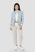 Woman wearing a blue floral Jacket over a white shirt with beige pants on a white background