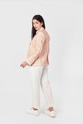 Woman wearing a pink textured jacket and white pants on a white background