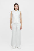 Woman wearing a white sleeveless top and wide-leg pants on a white background