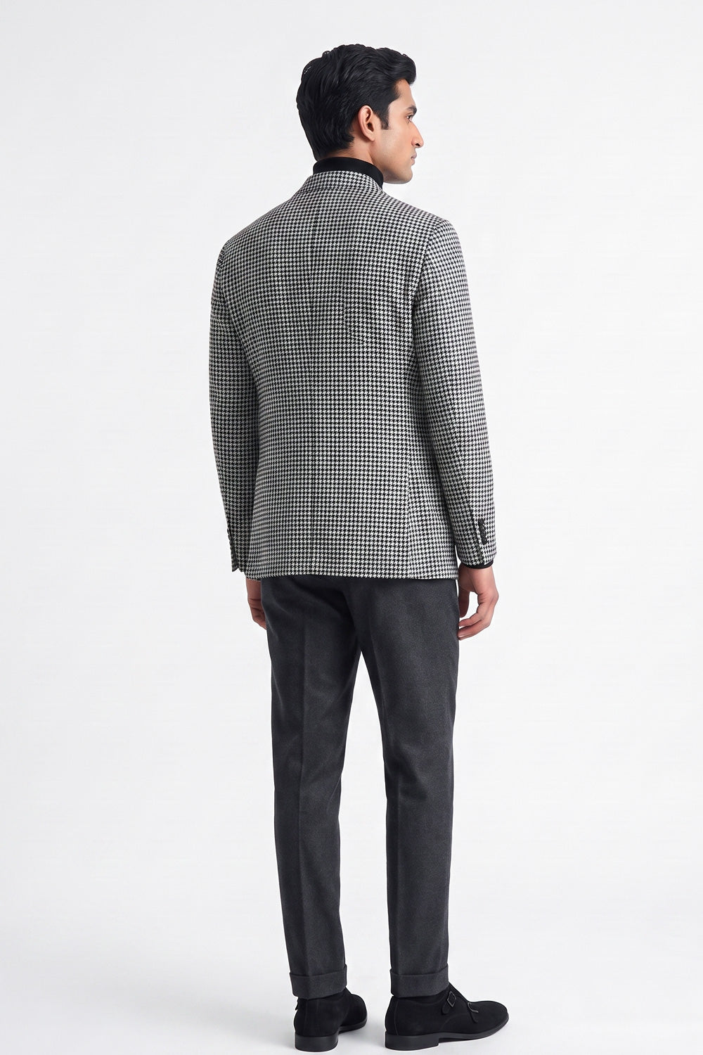 A man shown from the back wearing a black and white checks cotton blazer, dark gray trousers, and black shoes, photographed against a plain white studio background.