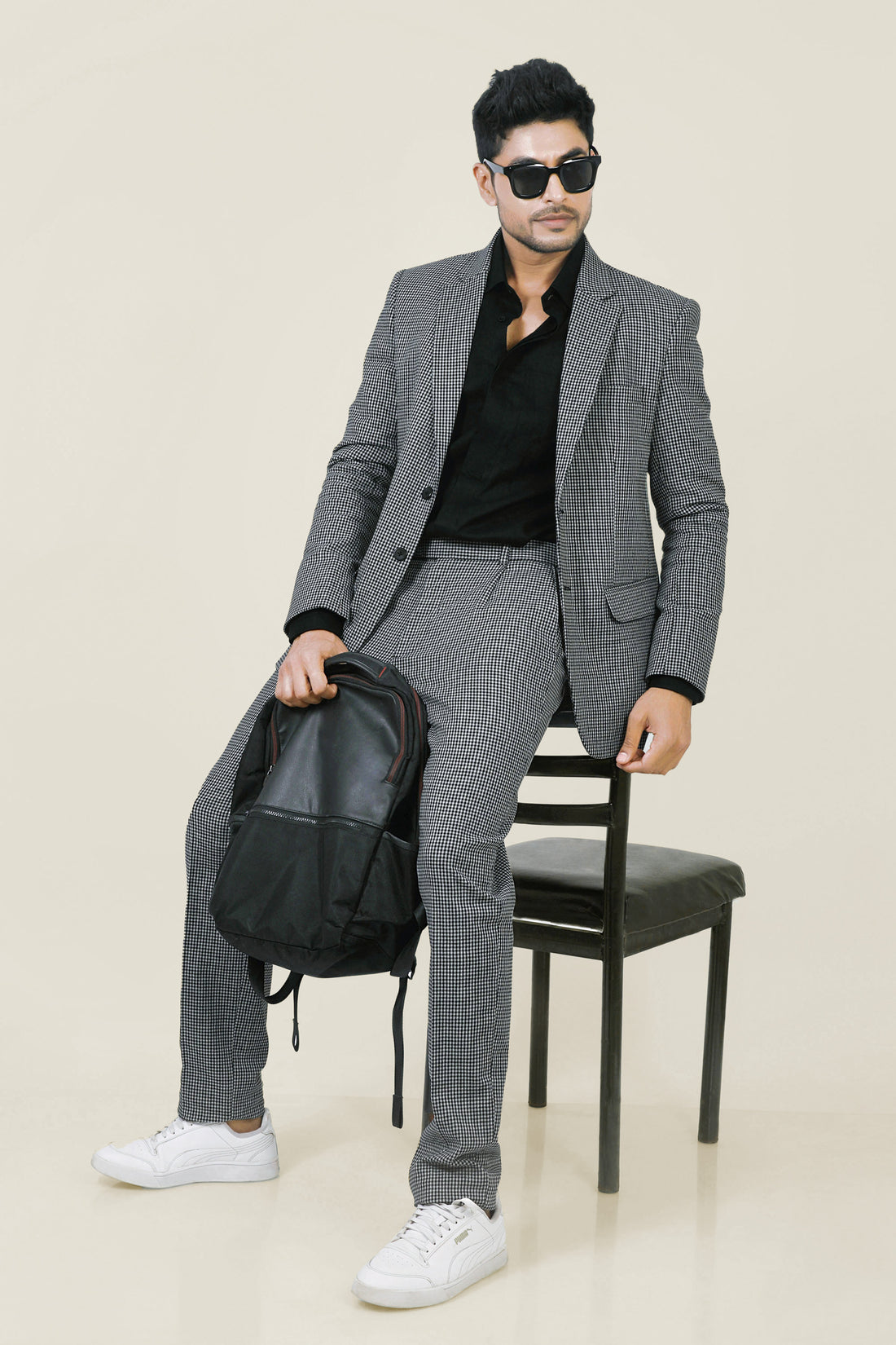 Stylish man in a gray and white checkered cotton jacket and pants, with a black shirt and white sneakers.