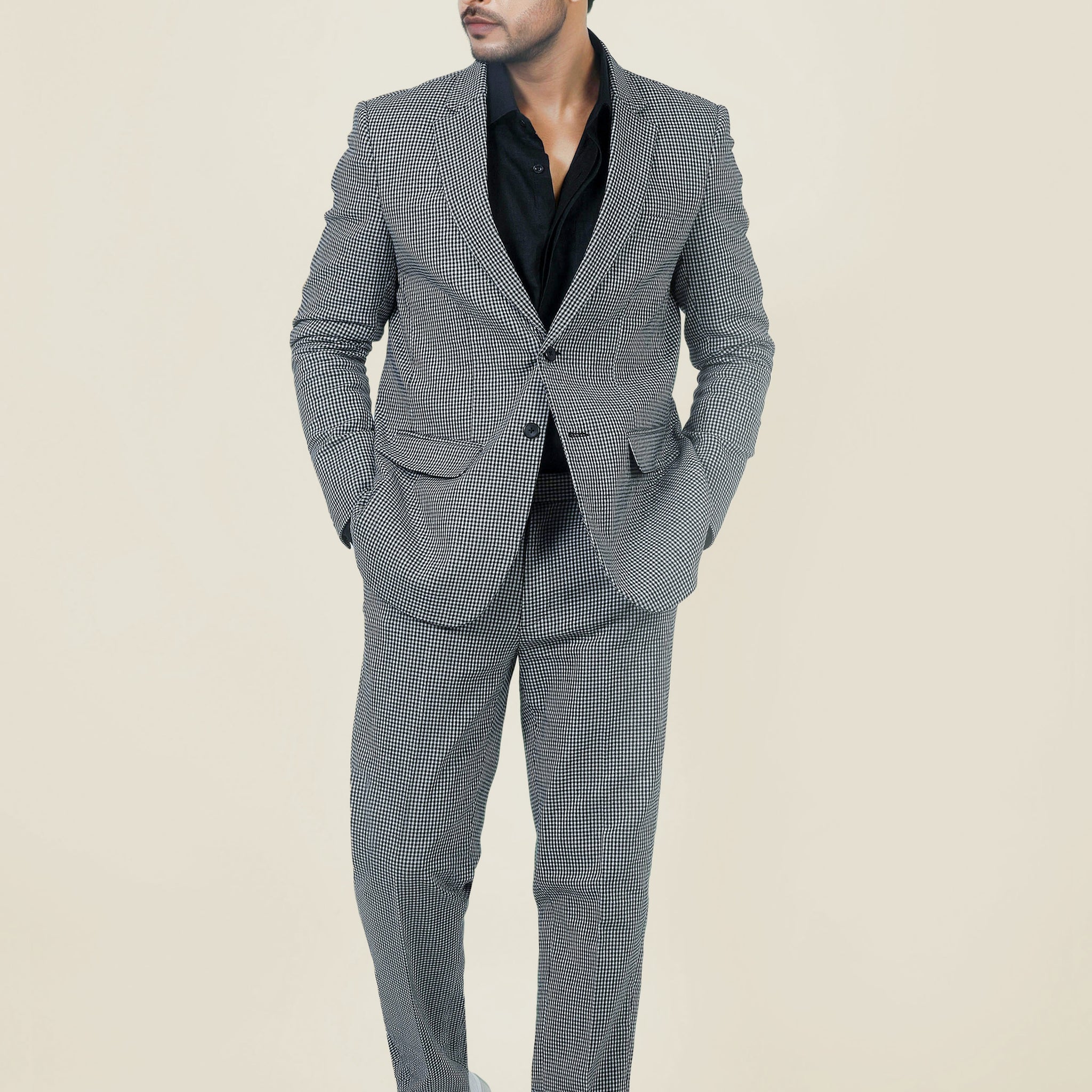 Stylish man in a gray and white checkered cotton jacket and pants, with a black shirt and white sneakers.